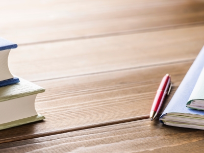 Books, pen and files on a wooden desk